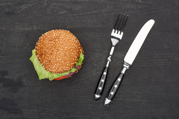 tasty fresh burger on wooden black table with cutlery