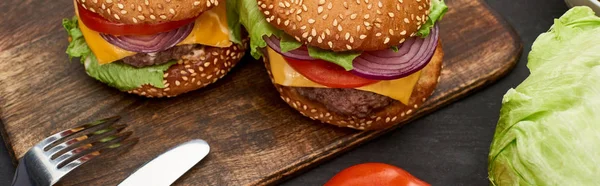 Smakelijke Verse Cheeseburgers Houten Bord Met Bestek Panoramisch Schot — Stockfoto