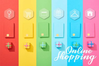 top view of multicolored empty credit cards and gift boxes on rainbow background with online shopping illustration