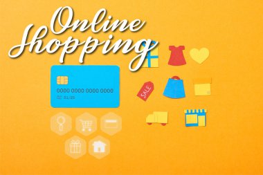 flat lay with blue credit card template near shopping icons isolated on orange with online shopping illustration
