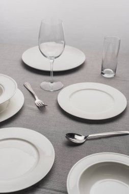 Gri yüzeyde boş bardaklarla yemek takımı servis ediyorum.