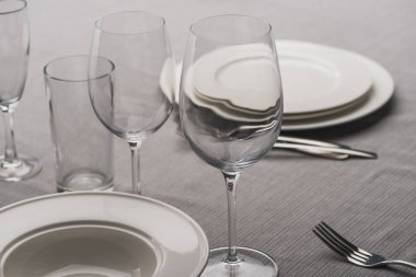 Serving dishware with glasses on grey tablecloth