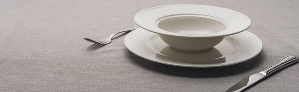 Two plates and cutlery on grey surface, panoramic shot