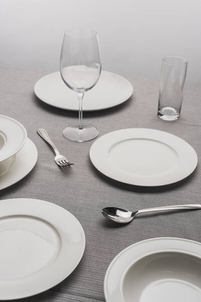 Serving dinnerware with empty glasses on grey surface