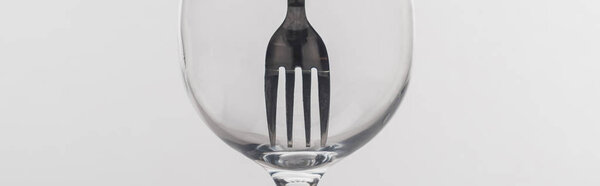 Panoramic shot of fork in clear wine glass isolated on grey