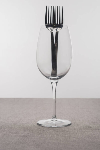 Вилки в прозрачном бокале вина на скатерти изолированы на сером
