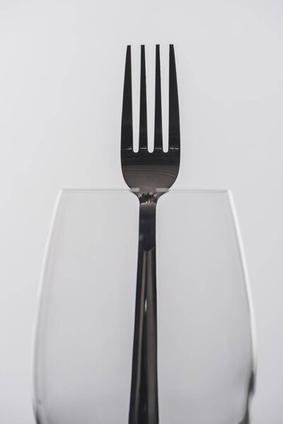 Selective focus of fork in wine glass isolated on grey