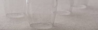 Panoramic shot of inverted wine glasses on grey cloth clipart
