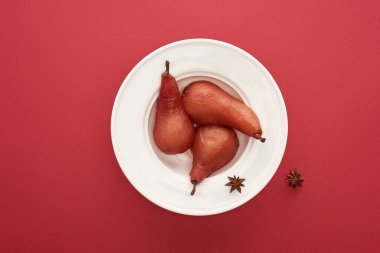 top view of delicious pear in wine with anise on plate on red background clipart