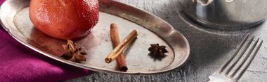 delicious pear in wine with cinnamon and anise on silver plate and in stewpot on grey concrete surface with pink napkin and fork, panoramic shot clipart