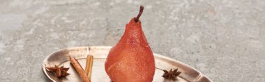 delicious pear in wine with cinnamon and anise on silver plate on grey concrete surface, panoramic shot clipart
