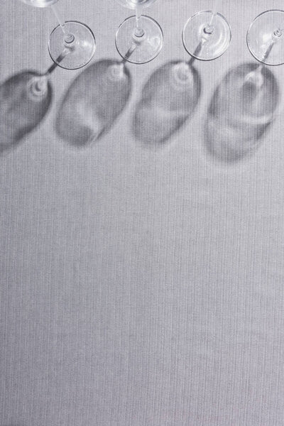 Top view of wine glasses with shadow on grey surface with copy space