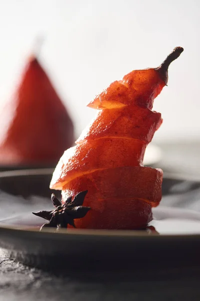 close up view of delicious sliced pear in wine with anise on plate