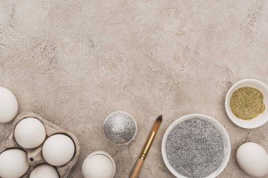 Tavuklu yumurta, gümüş ve altın parıltılı gri beton yüzeyde boya fırçaları.