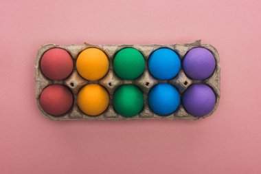 Pembe arka planda, karton kutuda boyanmış Paskalya yumurtalarının üst görüntüsü
