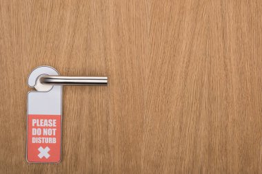 wooden hotel room door with please do no disturb sign on handle clipart