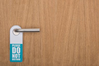 wooden hotel room door with please do no disturb sign on handle clipart