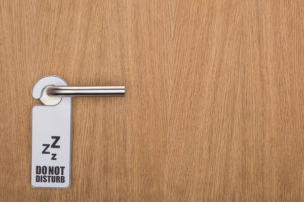 wooden hotel room door with do no disturb sign on handle