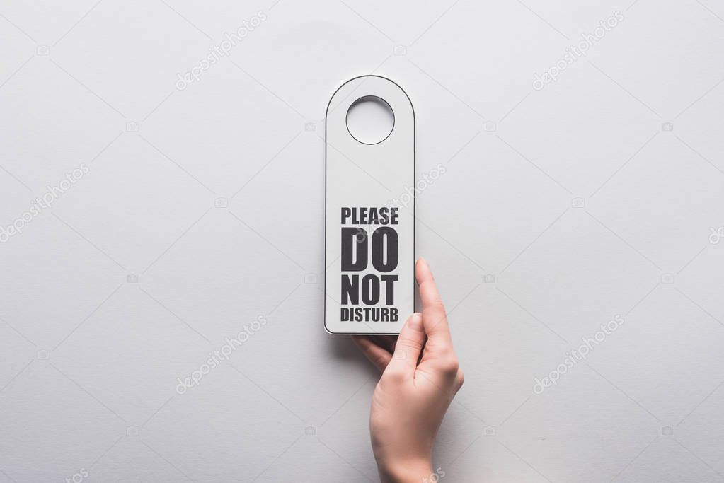 cropped view of woman holding please do no disturb sign on white background