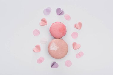 Beyaz üzerine izole edilmiş pembe badem kurabiyelerinin ve mor kalplerin üst görüntüsü.