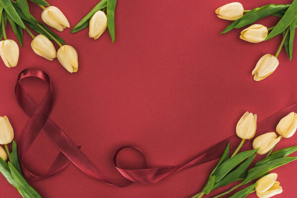 top view of tulips with silk ribbon isolated on red with copy space
