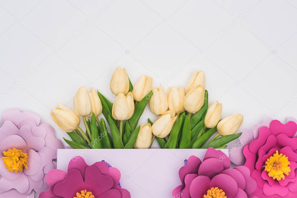 top view of tulips in violet shopping bag with paper flowers isolated on white
