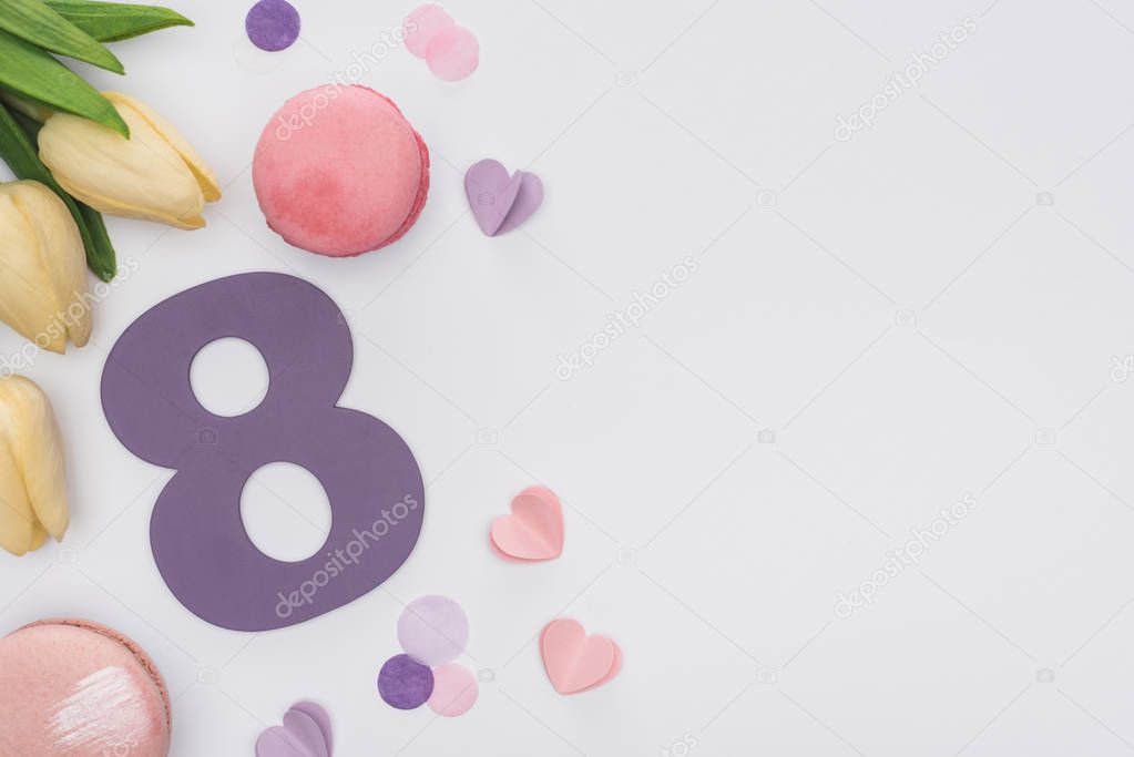 top view of tulips, pink macarons, confetti and number 8 isolated on white