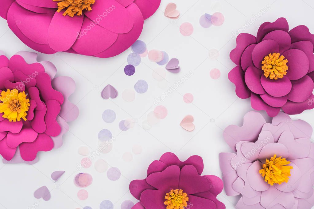 top view of paper cut pink and violet flowers near confetti isolated on white
