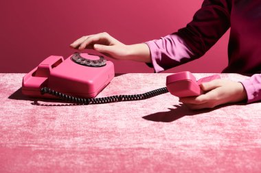 Kadının kadife kumaş üzerinde retro telefon kullanması görüntüsü pembe, kızsı bir konseptte izole edilmiş. 