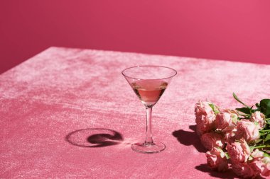 Gül şarabı buketin yanında kadife kumaş üzerinde pembe, kızsı bir konseptte izole edilmiş.