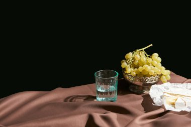 Camembert peyniri, üzüm ve su ile klasik natürmort masada kahverengi masa örtüsü siyah üzerine izole