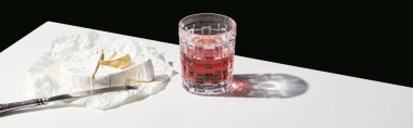 Camembert peyniri ve kırmızı şarapla klasik natürmort. Siyah, panoramik karede izole edilmiş beyaz masada.