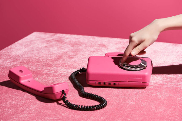 cropped view of woman using retro phone on velour cloth isolated on pink, girlish concept 