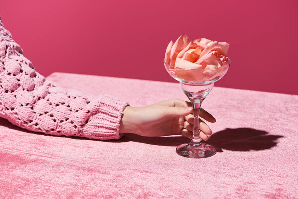 обрезанный вид женщины с лепестками в стекле на велюровой ткани, изолированной на розовой, девичьей концепции
 