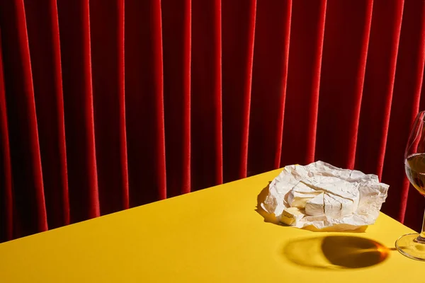 Kırmızı Perdenin Yanındaki Sarı Masada Camembert Yanında Kırmızı Şarap Kadehinin — Stok fotoğraf