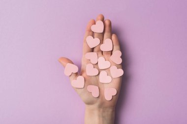 Kırpılmış menekşe arka planda pembe kağıt kalpler tutan kadın görüntüsü