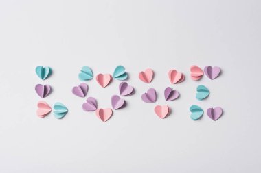 top view of love lettering made of colorful paper hearts on white background clipart