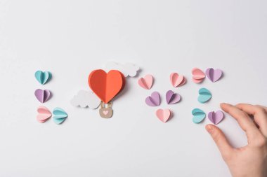 top view of love lettering made of colorful paper hearts and air balloon with clouds on white background clipart