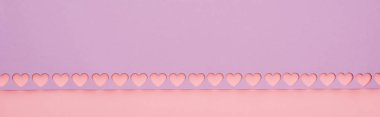top view of violet paper with cut out hearts on pink background, panoramic shot clipart