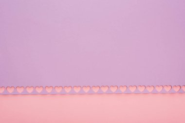 Pembe arka planda kesilmiş kalpleri olan menekşe kağıdının üst görünümü