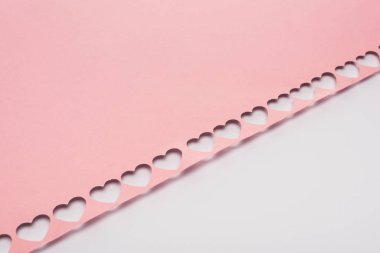 Beyaz arkaplanda kesilmiş kalpler olan pembe kağıt