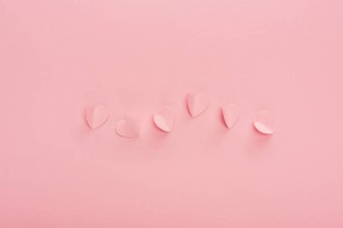 Pembe arka planda pembe kağıt kalplerin üst görünümü