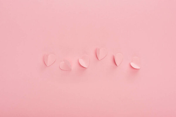 top view of pink paper hearts on pink background