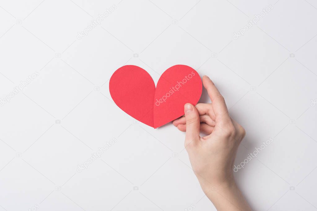 cropped view of woman holding red heart on white background