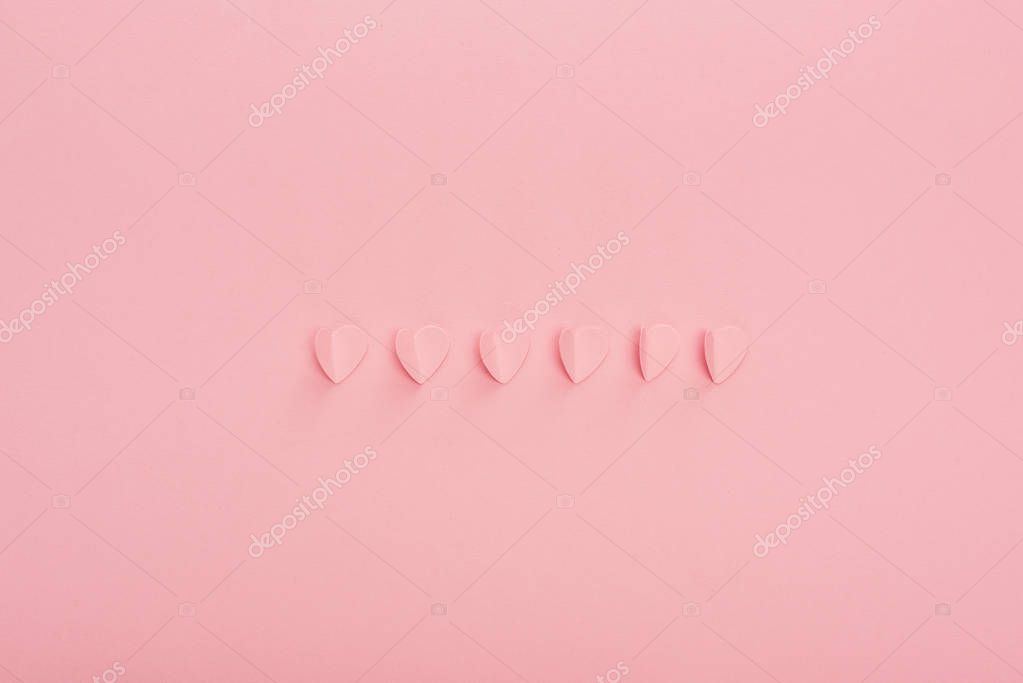 Top view of pink paper hearts on pink background