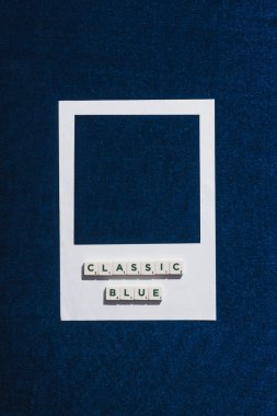Küpler üzerindeki klasik mavi harflerin üst görünümü ve mavi arkaplan desenli beyaz fotoğraf çerçevesi