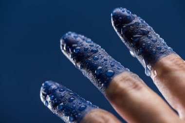 Islak, boyalı parmakları maviye boyanmış bir kadın eli.