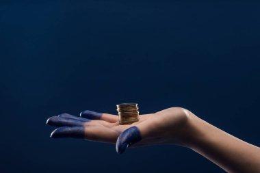 Kırpılmış kadın eli, mavi üzerinde izole edilmiş bozuk paraları tutan boyanmış parmaklar.