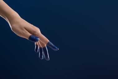 Kırpılmış kadın eli görüntüsü, mavi üzerine izole boyanmış parmaklar.