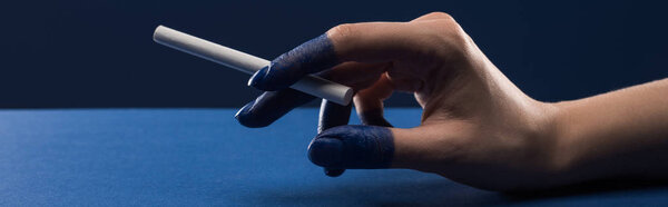 обрезанный вид женской руки с раскрашенными пальцами, держащими сигарету изолированный на голубом, панорамный снимок
